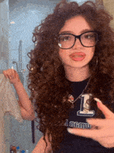 a girl with curly hair wearing glasses and a black shirt that says i