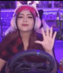 a woman wearing headphones and a bandana is sitting in a chair holding a steering wheel .