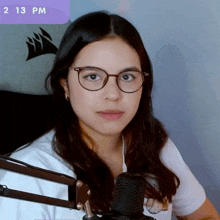 a woman wearing glasses and a white shirt stands in front of a microphone with a corsair logo in the background