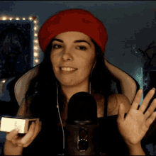 a woman wearing a red beret is holding a book in front of a black microphone
