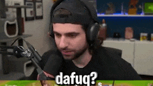 a man wearing headphones is sitting in front of a microphone and talking into it .