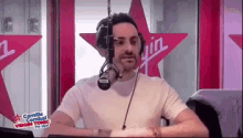 a man wearing headphones is sitting in front of a microphone in a radio studio .