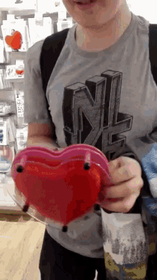 a boy wearing a grey shirt with nl on it holds a heart shaped object