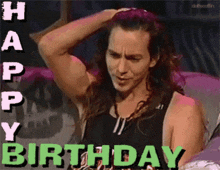 a man with long hair holds his hand to his head in front of a happy birthday sign