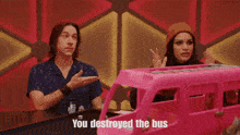 a woman in an elf costume is standing in front of a pink toy bus that says you destroyed the bus