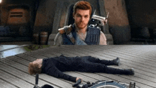 a man in a wheelchair is laying on a wooden floor next to a man in a suit .