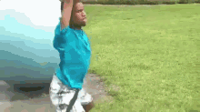 a young man in a blue shirt and white shorts is standing in a grassy field holding a blue ball .