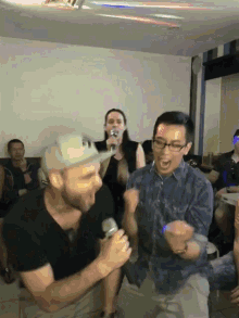 a man singing into a microphone with a woman singing behind him in a room