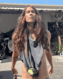a man with long hair is standing in front of a garage .