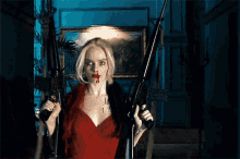 a woman in a red dress is holding a gun with blood on her face