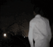 a person in a white coat is standing in a dark room