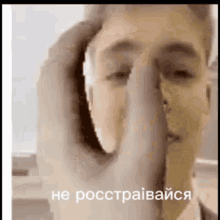 a close up of a person covering their face with their hand in a foreign language .
