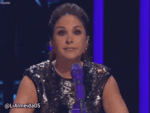 a woman in a sequined top is sitting in front of a purple microphone with the hashtag lialmeida05