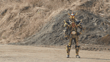 a man in a black and gold costume stands in a dirt field