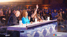 a group of people sitting at a table with nbc written on it