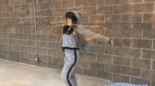 a person is standing in front of a brick wall with a tornado coming out of the wall .