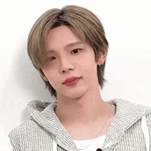a young man with blonde hair is wearing a striped hoodie and a necklace .