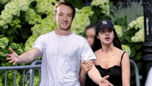 a man and a woman are standing next to each other in front of flowers .