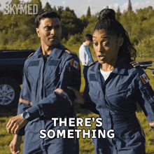 a man and a woman are walking in a field with the words there 's something written on the bottom