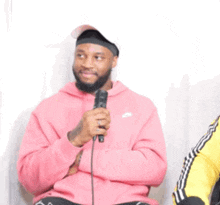 a man wearing a pink nike hoodie holds a microphone