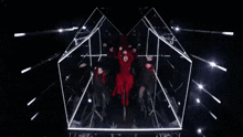 a woman in a red dress is dancing in a cube with a group of people .