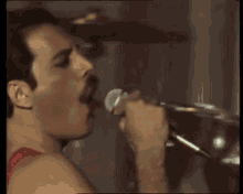 a close up of a man singing into a microphone .