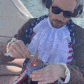 a man in an american flag costume is holding a hot dog in a cup