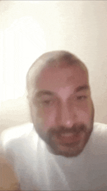 a man with a beard is wearing a white shirt and smiling .