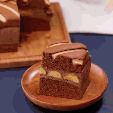 a slice of chocolate cake with bananas on it on a wooden plate