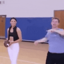 a man and a woman are playing with a football in a gym