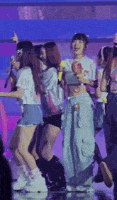a group of young women are dancing on a stage and one of them is wearing a shirt that says ' a ' on it