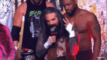 a man with long hair and a beard is talking into a microphone while wearing a shirt that says edwards