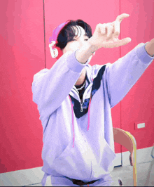 a man wearing headphones and a purple sweatshirt makes a funny face