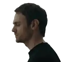 a man with a beard is wearing a black shirt and looking down