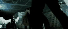 a man with angel wings is standing in a dark room next to a man in a suit .
