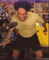 a man wearing a yellow shirt and black shorts is dancing in front of a microphone .