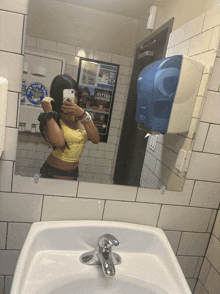 a woman is taking a picture of herself in a bathroom mirror with a poster on the wall that says ' better together '
