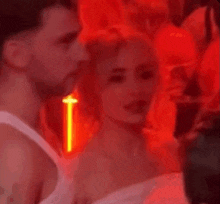 a group of people are standing in a dark room with red lights behind them .