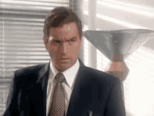 a man in a suit and tie is looking at the camera .