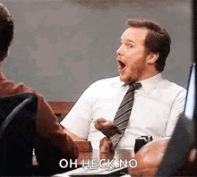 a man in a suit and tie is sitting at a table with his mouth open and says `` oh heck no '' .