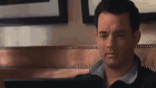 a man is sitting at a table looking at a computer screen .