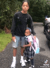 a boy is holding a little girl who is wearing a school uniform and backpack