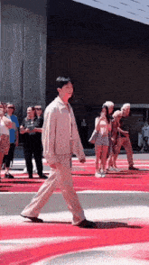 a man is walking on a red carpet in front of a crowd