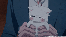 a man is holding a small white cat in his hands