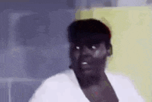 a woman in a white shirt is making a funny face while looking at the camera .