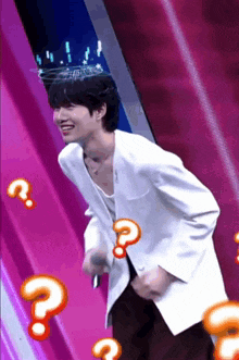 a man in a white jacket is laughing with a question mark around his head .