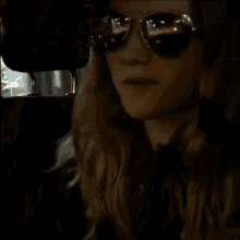 a woman wearing sunglasses holds a piece of paper