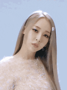 a woman with long blonde hair is wearing a sweater and a hair clip