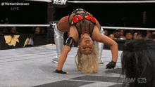 a woman is doing a handstand in a wrestling ring with the aew logo behind her