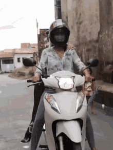 a woman wearing a helmet is riding a white motorcycle